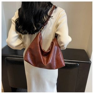 Detail of vintage reddish-brown hobo bag with knotted shoulder strap and gold logo text