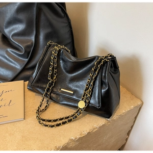 Détail du sac hobo en cuir noir grainé avec chaînes dorées et ornements métalliques