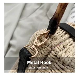 Detail of woven straw bag featuring bamboo handle, metal hooks and leather strap