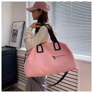 Detail of pink quilted travel bag showing diamond pattern stitching and black wide handles