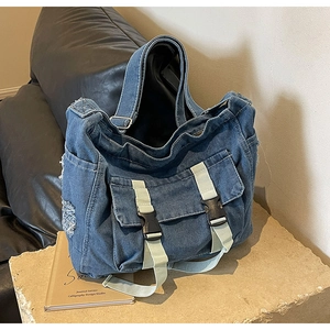 Détail du sac fourre-tout en jean bleu avec poches cargo, bords effilochés et boucles en plastique