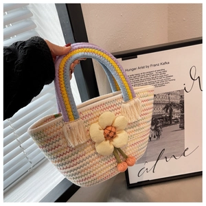 Détail d'un sac seau tissé avec poignée arc-en-ciel et grande fleur jaune en tissu