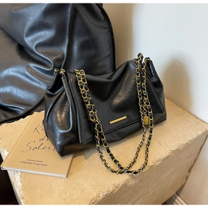 Détail de la texture en cuir PU noir avec chaîne dorée et boucle sur sac à bandoulière
