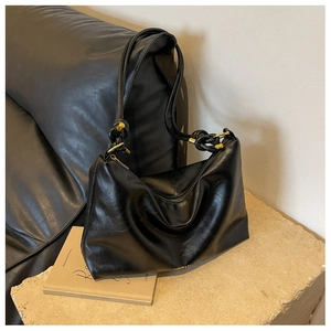 Detail of black hobo bag with knotted strap and gold metallic accents on stone