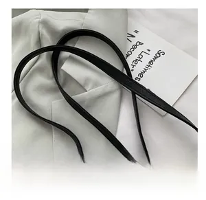 Detail showing the black litchi pattern leather shoulder strap on a grey suit jacket