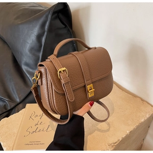 Macro view of brown lychee grain leather handbag with gold twist lock and fine stitching