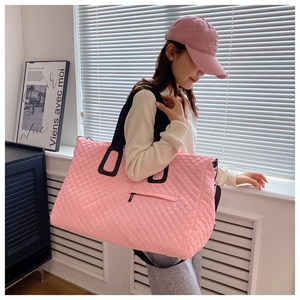 Detail of pink quilted travel bag with classic diamond stitching and black straps