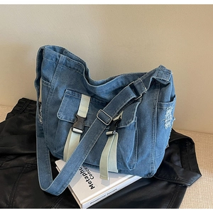 Vue détaillée du sac bandoulière en denim bleu avec boucles cargo et bords effilochés