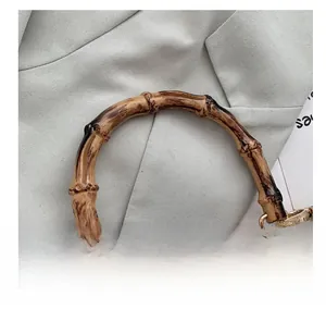 Detail of natural bamboo handle and black leather strap on woven straw bag