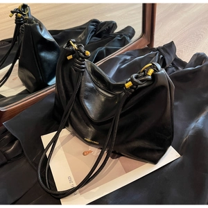 Detail of knotted shoulder strap and gold hardware on black leather tote bag