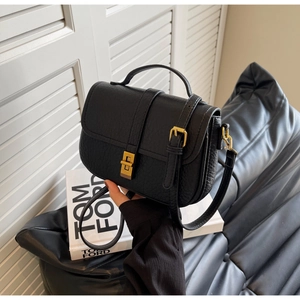 Detail of black lychee grain leather handbag with vintage gold buckle and top handle