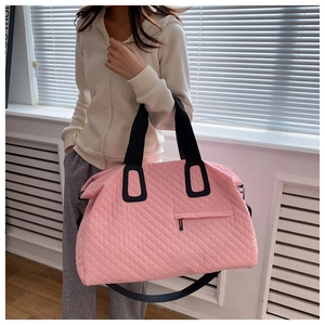 Detailed view of pink quilted duffel bag with wide straps and spacious interior for travel