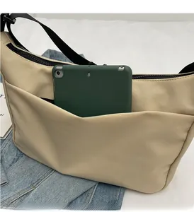 Detail view of beige nylon crossbody bag featuring a front pocket for a 10-inch tablet