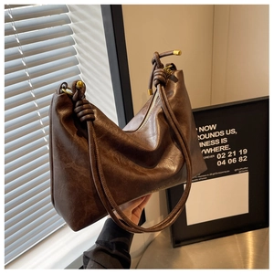 Detail of soft dark brown vintage leather tote with decorative knots and golden hardware