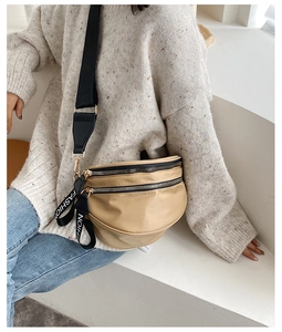 Detail of a beige crescent nylon crossbody bag with dual-zipper layers and fashion strap