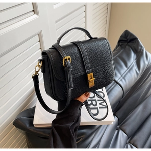 Detail of black lychee grain leather handbag with gold square twist lock and hardware
