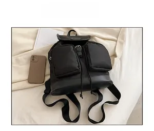 Flat lay of black nylon backpack with leather flap and drawstring closure details