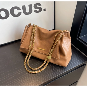 Detail of caramel brown PU leather bag with lychee texture and gold metal buckle