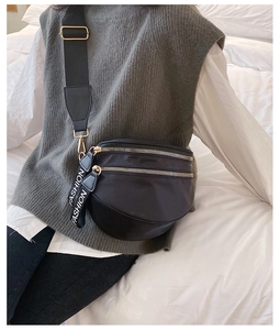 Close-up of black nylon crossbody bag with gold zippers and fashion lettering ribbon
