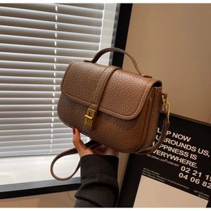 Macro detail of dark brown litchi pattern leather bag with vintage golden metal clasp