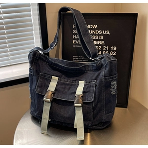Détail du sac cabas en denim bleu avec sangles vertes, boucle et coutures contrastées