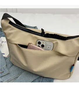 Close-up of beige nylon crossbody bag showing large internal space for wallet and phone