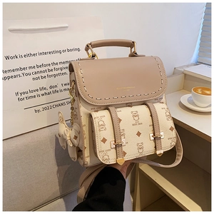 Détail du sac à dos en similicuir beige avec imprimé ours et breloque noeud papillon