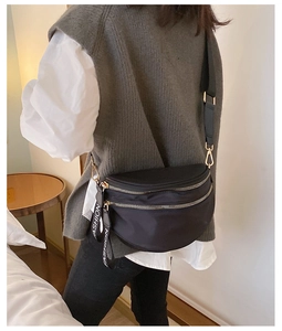 Detail of black nylon crescent bag showing double zippers and adjustable shoulder strap