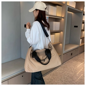 Side view of large khaki quilted tote bag on model showing storage capacity and shoulder strap