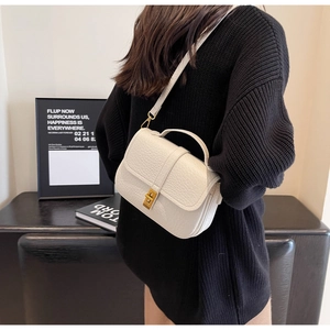 Litchi texture white crossbody bag with gold metallic lock shown on a model
