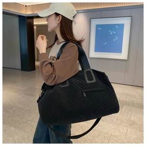 Detail of black quilted travel bag with reinforced straps and large capacity