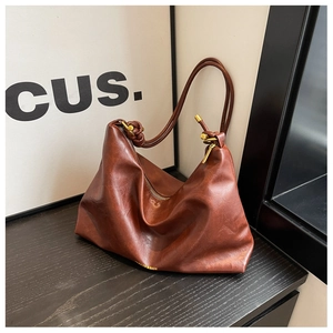 Detail of caramel leather tote bag with gold hardware and stylish knotted shoulder strap