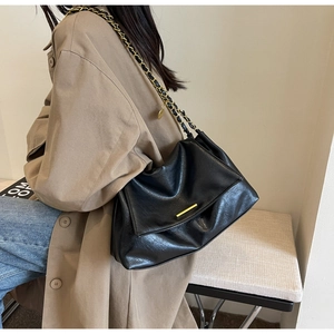 Détail du sac bandoulière en similicuir noir avec barre dorée et bandoulière chaîne