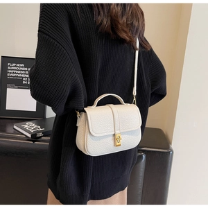 Detail of white litchi pattern crossbody bag with metal lock and fine shoulder strap
