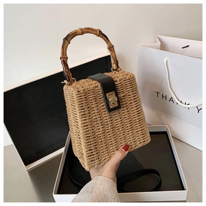 Close-up of woven straw handbag with bamboo handle and leather clasp detail