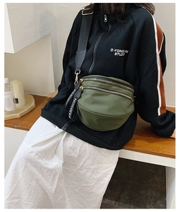 Detail of army green nylon crossbody bag with three zipper pockets and wide black strap