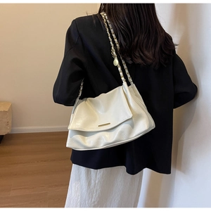 Detail of cream white oversized crossbody bag with gold chain strap and soft leather folds
