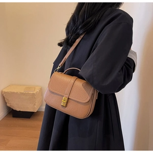 Detailed view of brown lychee grain faux leather bag with gold clasp and top handle