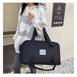 Detail of black quilted travel bag featuring wave patterns and adjustable shoulder strap