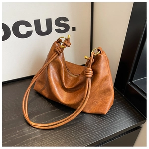 Close-up of caramel brown hobo bag showing knotted strap and gold ring hardware detail