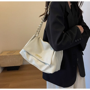 Détail du sac fourre-tout blanc crème avec chaîne dorée et texture cuir sur le modèle