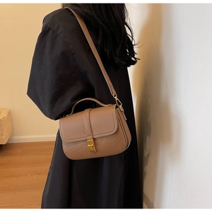 Detail of vintage caramel leather crossbody bag with gold twist lock on black coat