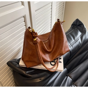 Detail of brown soft leather tote showing knotted strap and gold metallic hardware