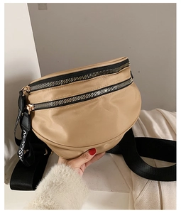 Detail of khaki nylon crossbody bag with black dual zippers and FASHION logo strap