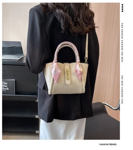 Détail du sac seau en cuir beige avec poignée en foulard de soie et fermoir doré