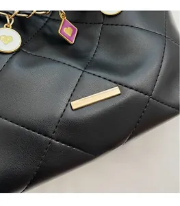 Détail du cuir matelassé noir avec matériel doré et breloques en cœur émaillé coloré