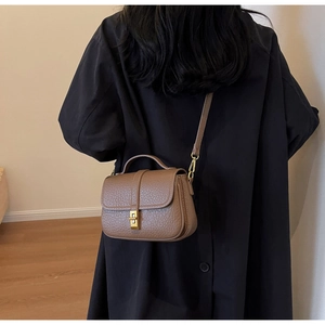 Brown pebble grain crossbody bag featuring a golden twist-lock closure and leather handle