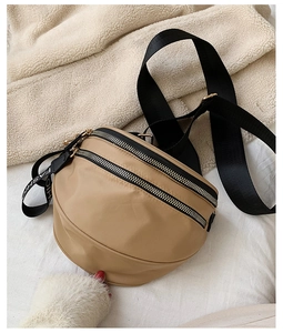 Detailed close-up of khaki nylon crescent bag with double zippers and fashion strap