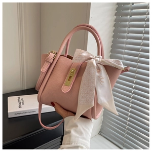Detail of pink lychee leather handbag with golden twist lock and decorative silk scarf