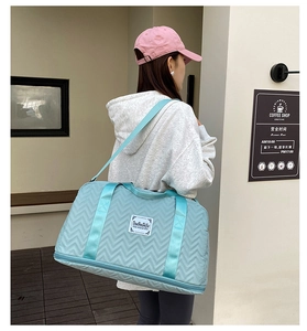 Detailed view of light blue quilted travel bag with adjustable strap and top handles